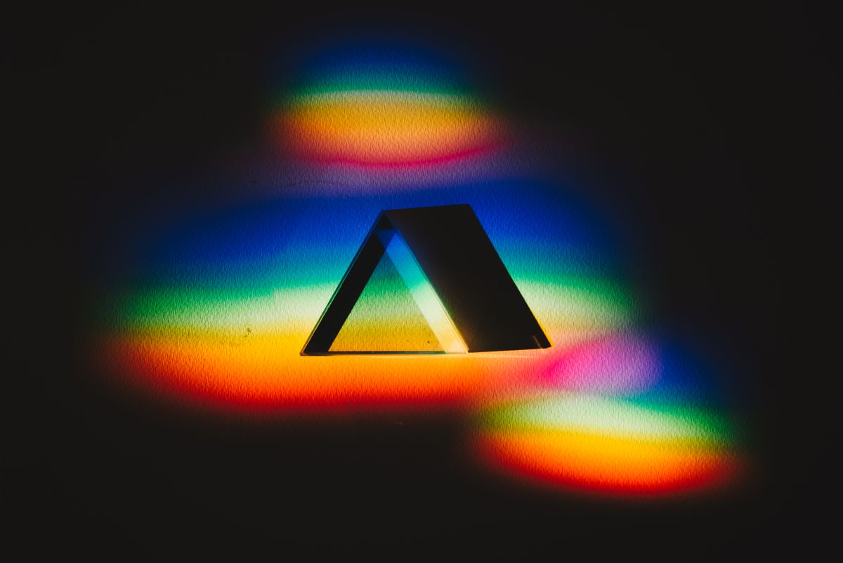 Colorful dispersion of light through a prism creating a vibrant rainbow spectrum on a dark background
