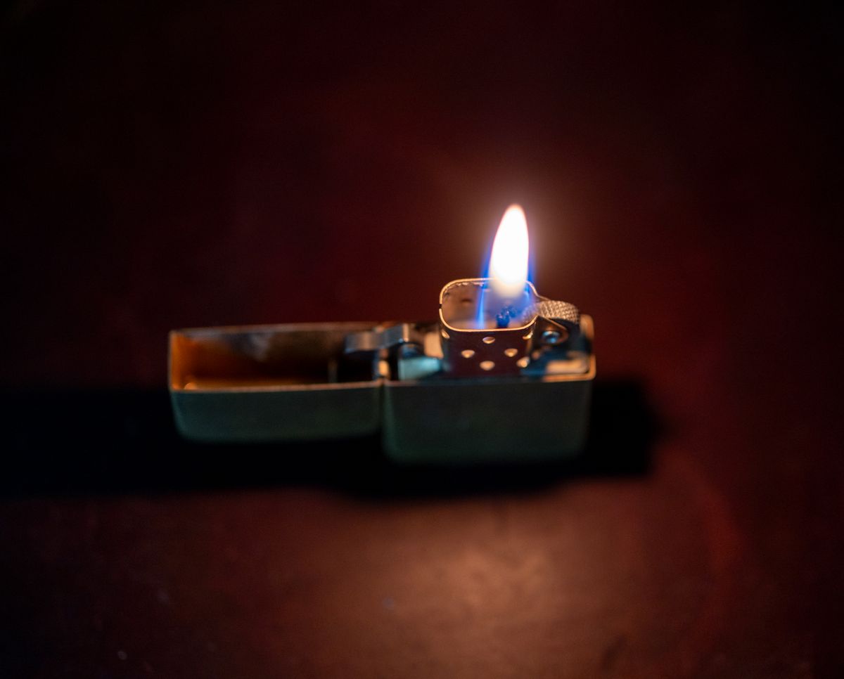 A metallic lighter burning with a bright flame, showing how a butane lighter works