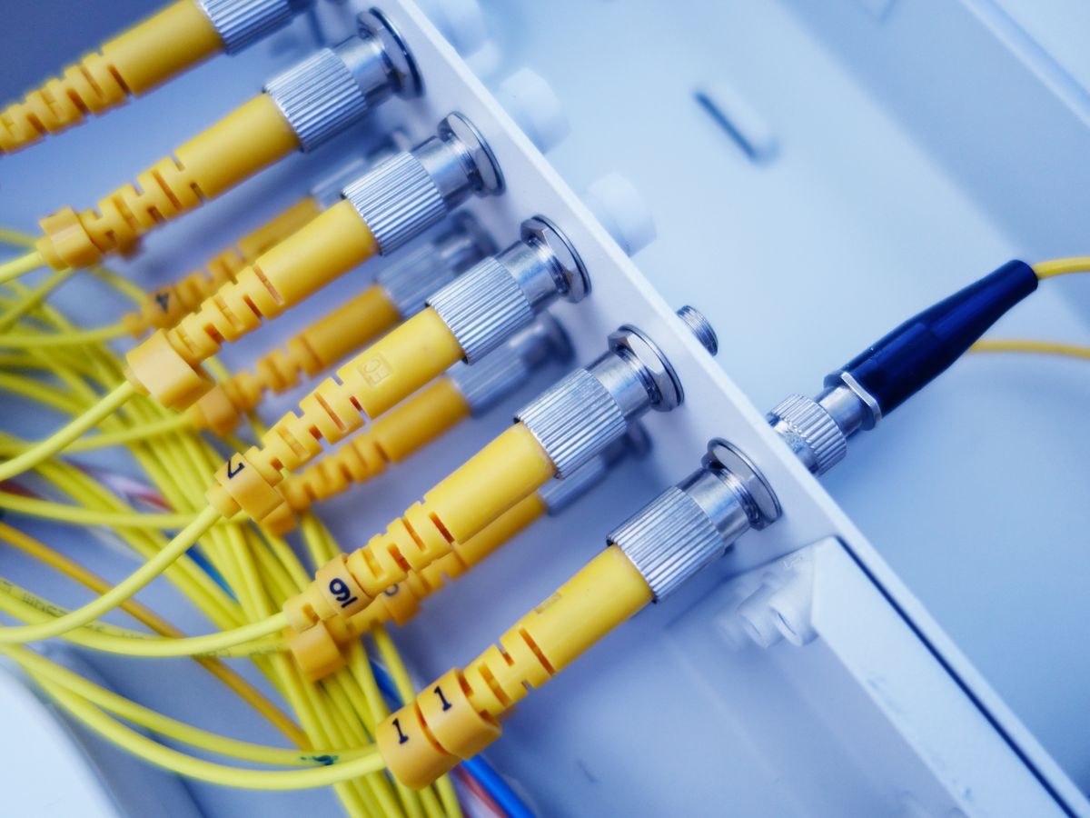 Yellow fiber optic cables connected to network server equipment demonstrating how fiber optic cable is assembled into usable network infrastructure
