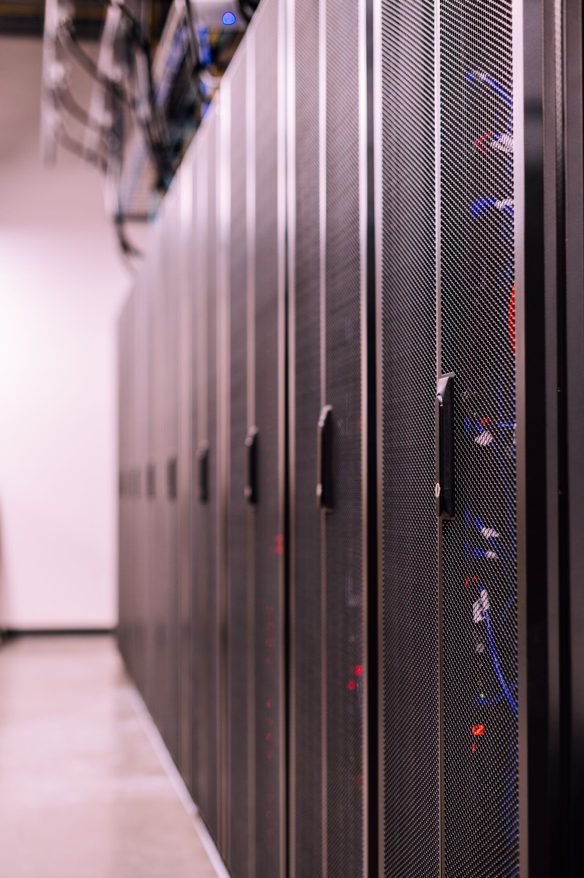 Row of similar lockers with various optic fiber cables in modern data server room, showing what is optical fiber in a real-world data center environment