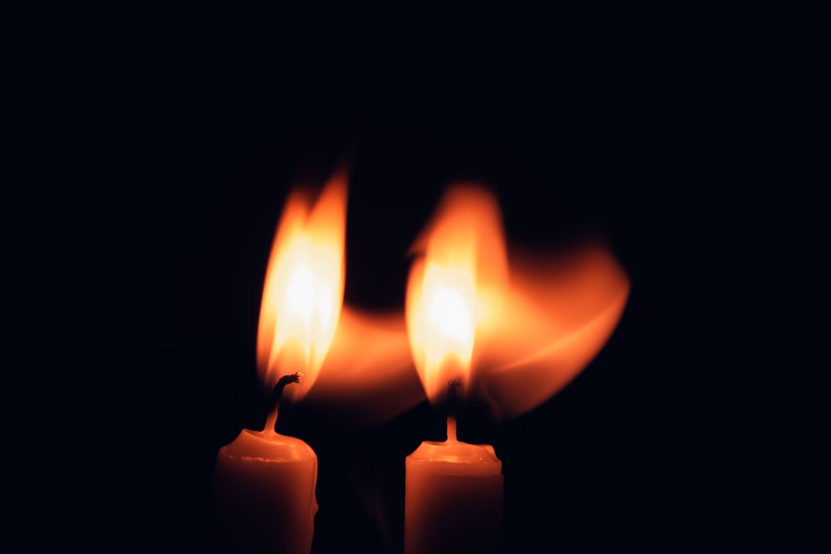 A candle flame giving off light and heat in a dark room
