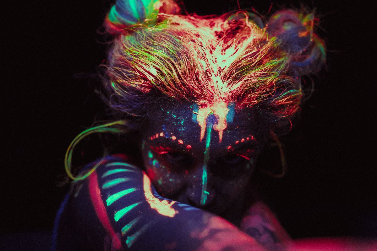 A face glowing under blacklight, showing fluorescence from ultraviolet light